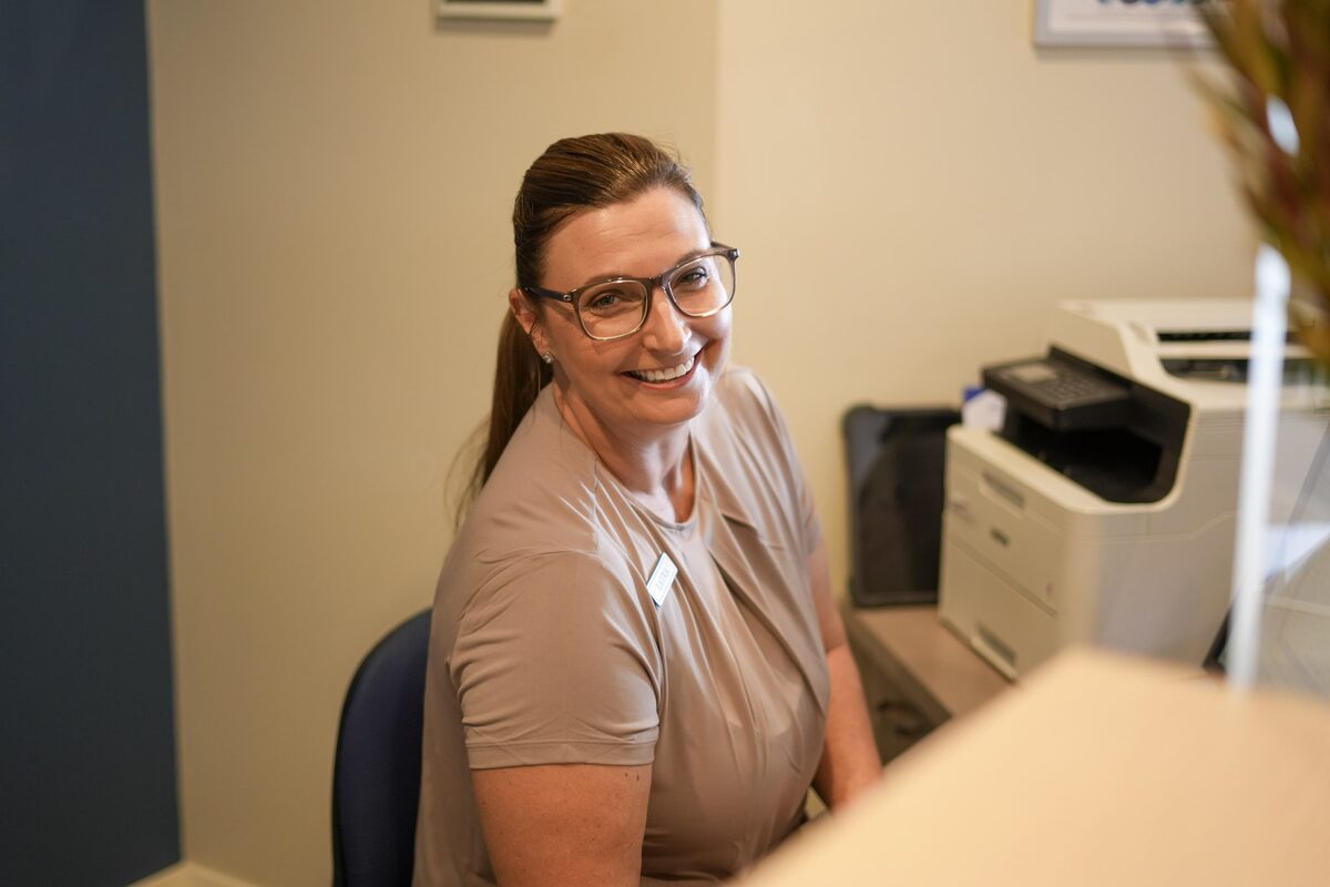Laura, Practice Manager, smiling at the front desk at Australind Dental Centre